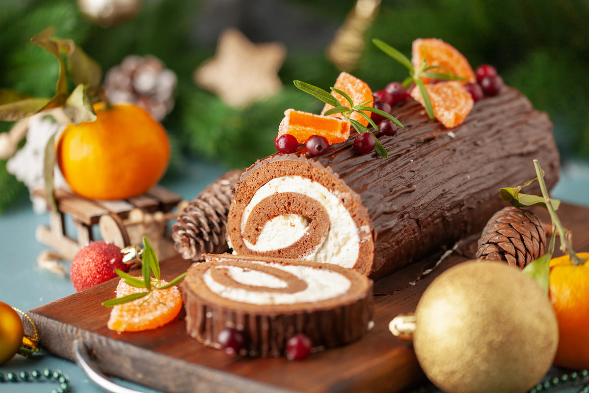 Bûche roulée de Noël au chocolat, garnie de crème vanille, décorée de copeaux de chocolat et sucre glace.