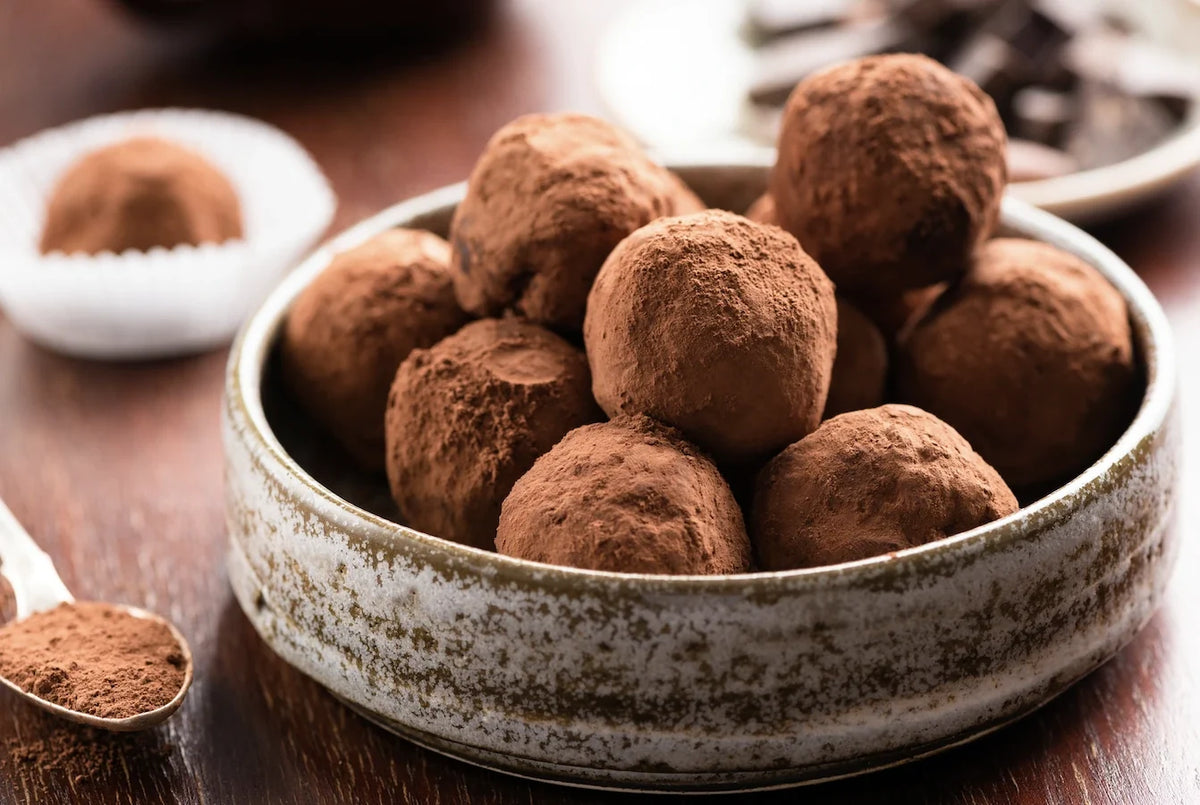 Truffes au chocolat maison roulées dans du cacao, noix de coco et éclats de noisettes, présentées en caissettes festives.