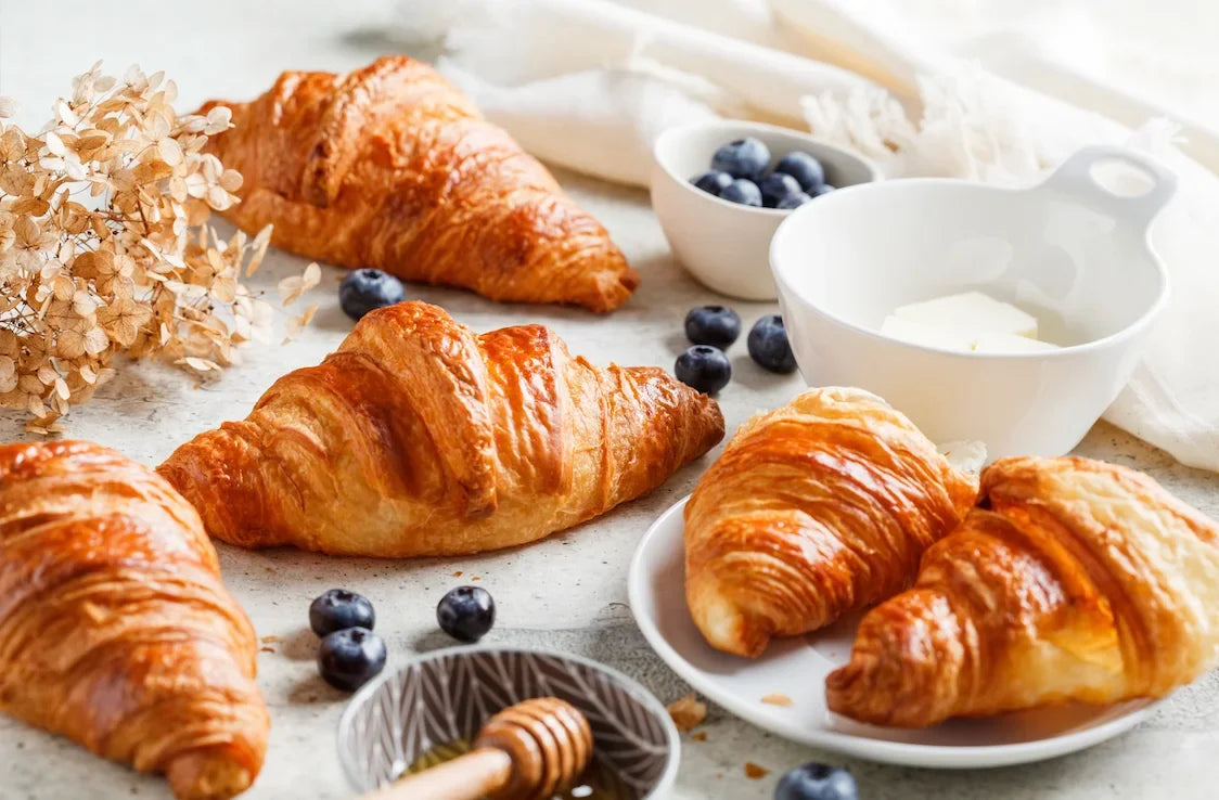 Croissants dorés maison, feuilletés et croustillants, sortant du four sur une plaque de cuisson.