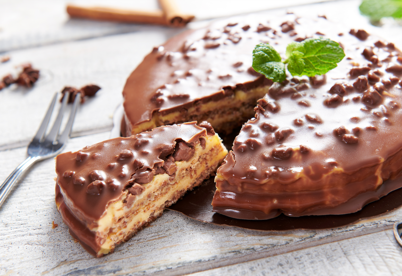 Une part de tarte au Daim sur une assiette blanche, révélant des couches de biscuit émietté, de caramel onctueux et de chocolat au lait, parsemée de morceaux de Daim émiettés.