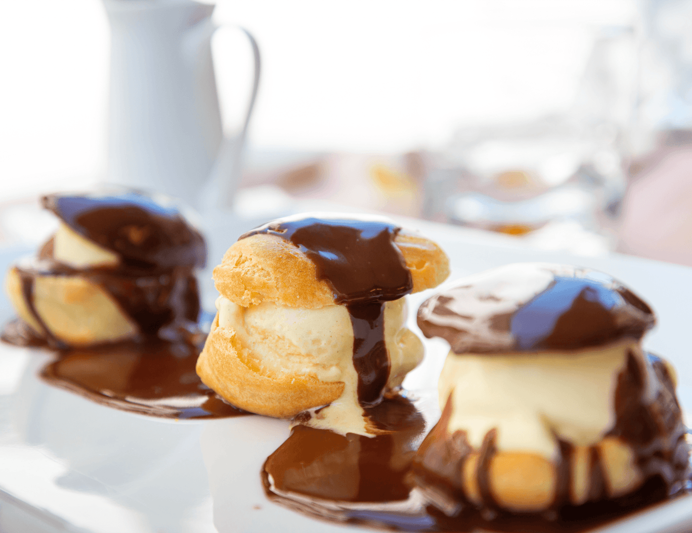 Assiette de profiteroles garnies de crème pâtissière et nappées de sauce au chocolat chaud